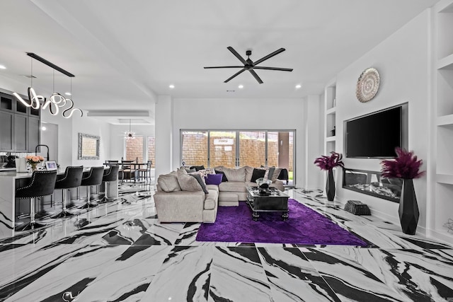 living room featuring built in shelves and ceiling fan with notable chandelier