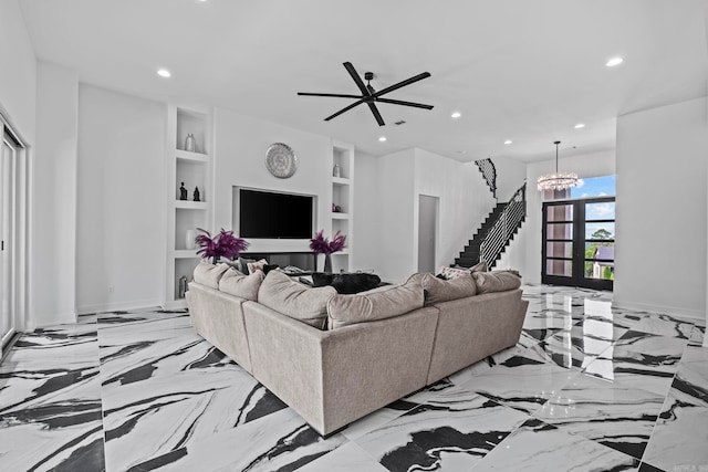 living room with built in features and ceiling fan with notable chandelier