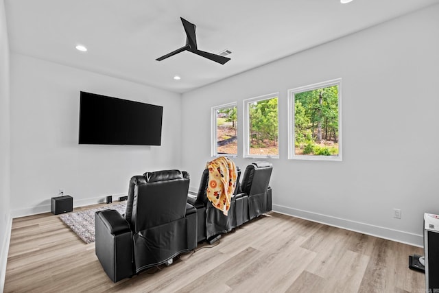 cinema room with light hardwood / wood-style flooring and ceiling fan