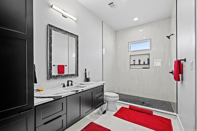 bathroom featuring vanity, toilet, and a tile shower