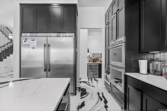 kitchen with stainless steel appliances, backsplash, light stone counters, and beverage cooler