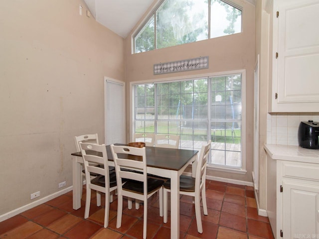 tiled dining room featuring high vaulted ceiling