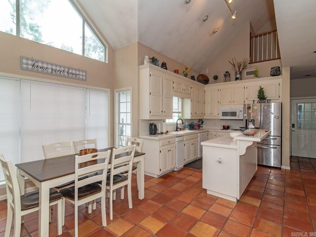 kitchen featuring white appliances, a center island, high vaulted ceiling, and backsplash