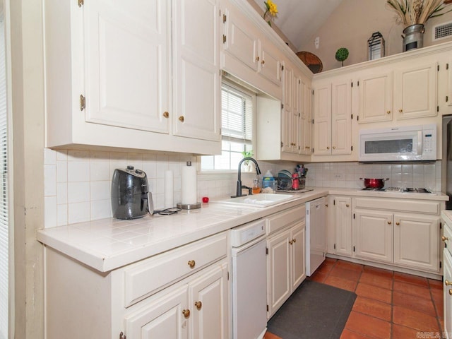 kitchen with tile countertops, decorative backsplash, sink, and white appliances