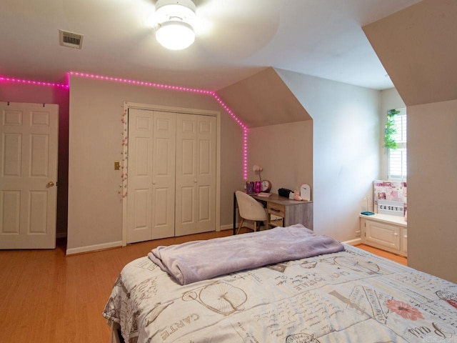 bedroom featuring light hardwood / wood-style floors, vaulted ceiling, and a closet