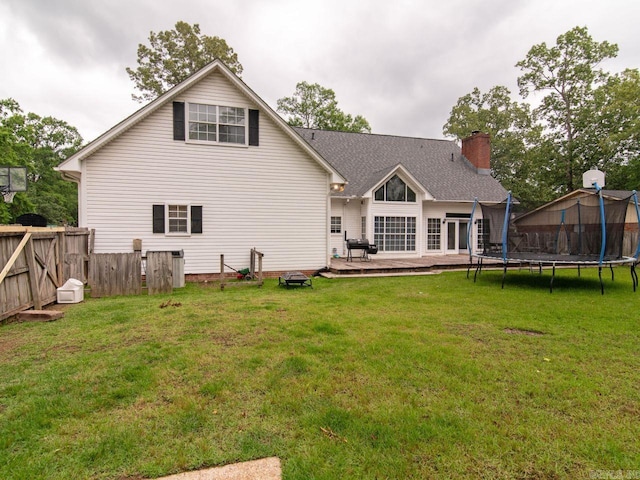 back of house featuring an outdoor fire pit, a lawn, and a trampoline