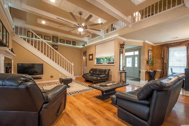 living room with crown molding, hardwood / wood-style floors, ceiling fan, and a high ceiling