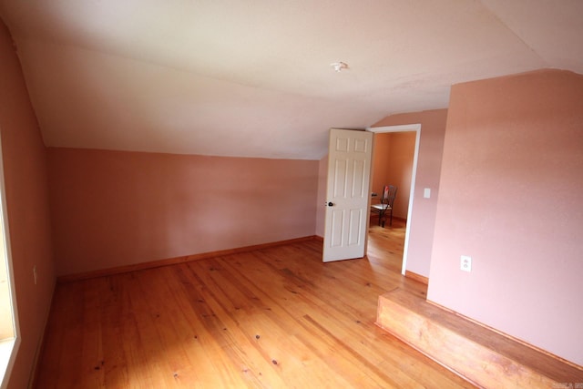 additional living space with lofted ceiling, light wood-style flooring, and baseboards