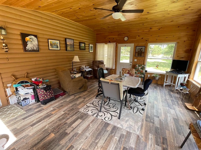 dining room featuring wood-type flooring, rustic walls, ceiling fan, and wood ceiling