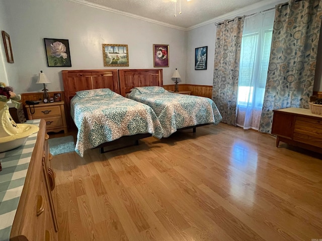 bedroom featuring a textured ceiling, light hardwood / wood-style flooring, and crown molding