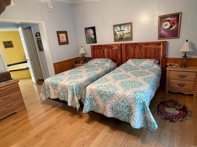 bedroom featuring ornamental molding, light hardwood / wood-style flooring, and connected bathroom