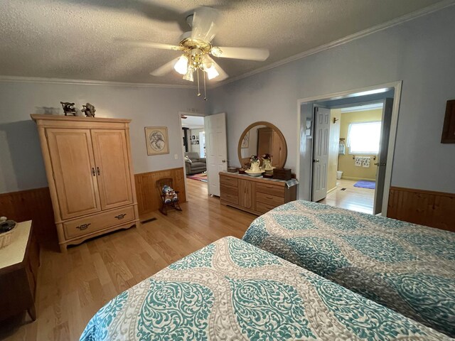 bedroom with light hardwood / wood-style flooring, ensuite bathroom, ceiling fan, ornamental molding, and a textured ceiling