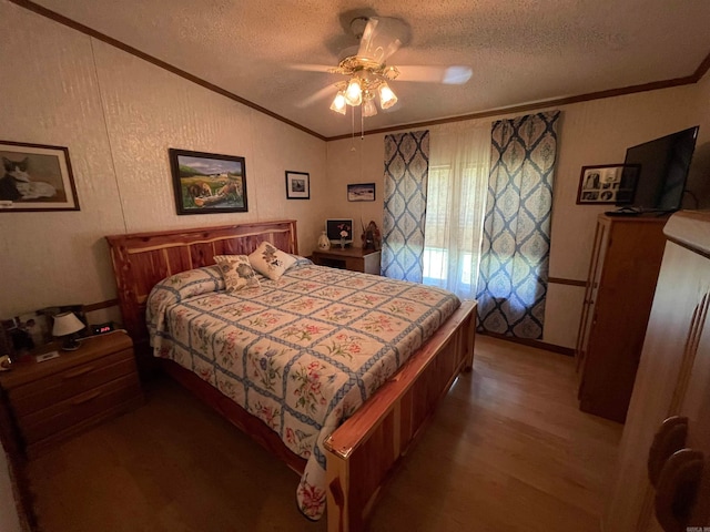 bedroom with a textured ceiling, ornamental molding, wood-type flooring, ceiling fan, and vaulted ceiling