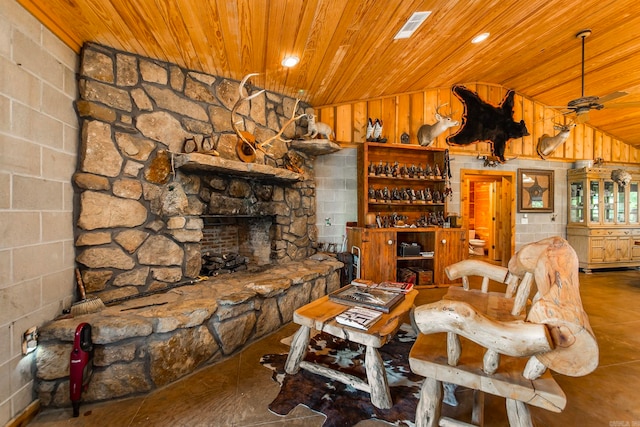 living room with wood ceiling, ceiling fan, wooden walls, a stone fireplace, and lofted ceiling