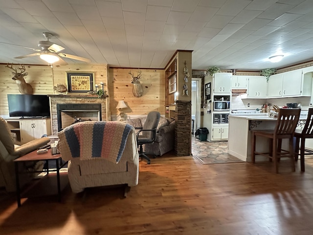 living room with dark hardwood / wood-style flooring, ceiling fan, and wooden walls