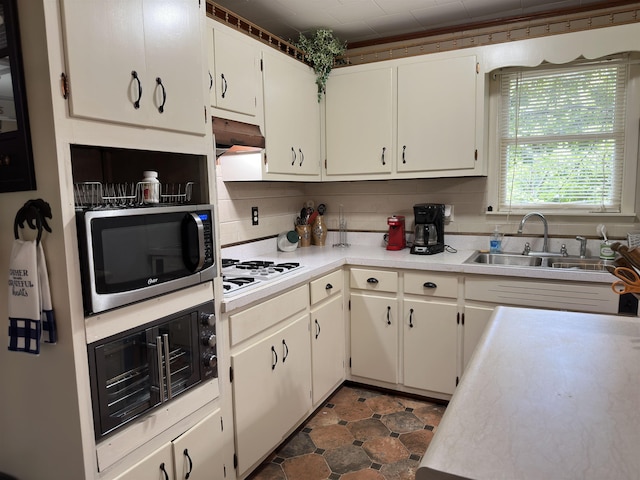 kitchen with white cabinets, white gas stovetop, and sink