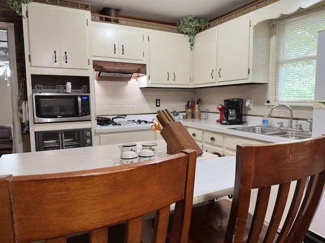 kitchen with white gas cooktop, sink, decorative backsplash, white cabinetry, and beverage cooler