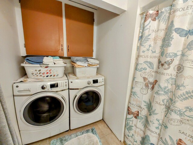 washroom with cabinets, washing machine and dryer, and light tile patterned floors