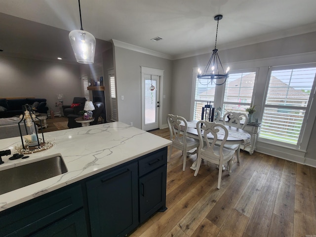 kitchen featuring a notable chandelier, wood-type flooring, light stone countertops, and hanging light fixtures