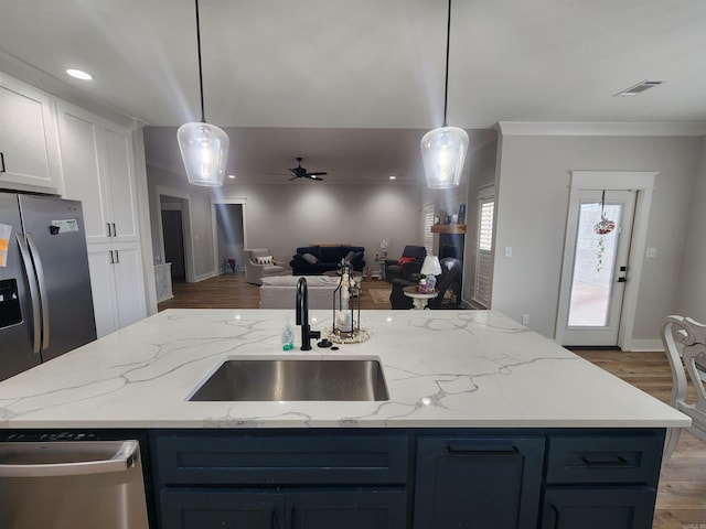 kitchen featuring white cabinets, sink, stainless steel appliances, and hanging light fixtures