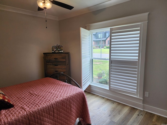 bedroom with light hardwood / wood-style floors, multiple windows, crown molding, and ceiling fan