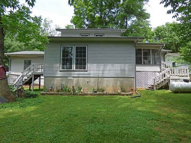 rear view of house with a wooden deck, a sunroom, and a yard