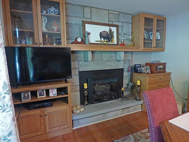 living room featuring a stone fireplace and hardwood / wood-style floors