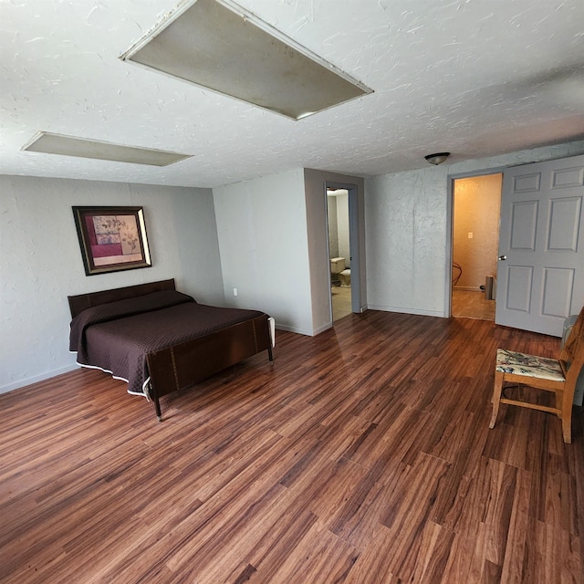 bedroom featuring ensuite bathroom, a textured ceiling, and wood-type flooring