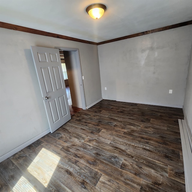 unfurnished room with crown molding and dark wood-type flooring