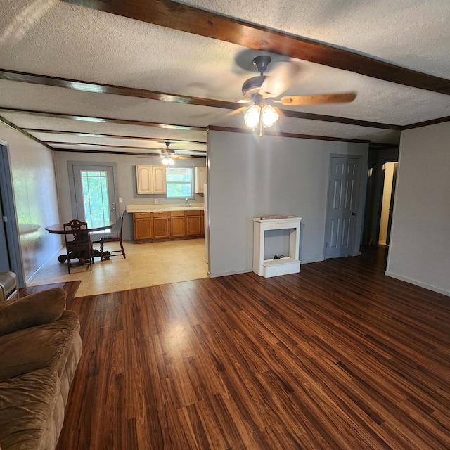 unfurnished living room with sink, tile flooring, ceiling fan, and a textured ceiling