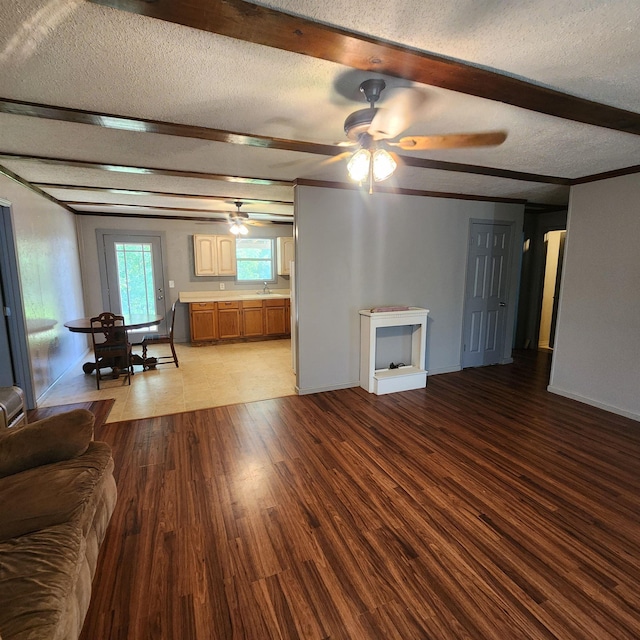1947 63rd Hwy, Hardy, AR 72542 - unfurnished living room featuring a sink, wood finished floors, a textured ceiling, beamed ceiling, and ceiling fan