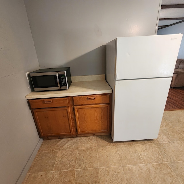 kitchen with white refrigerator and light tile floors