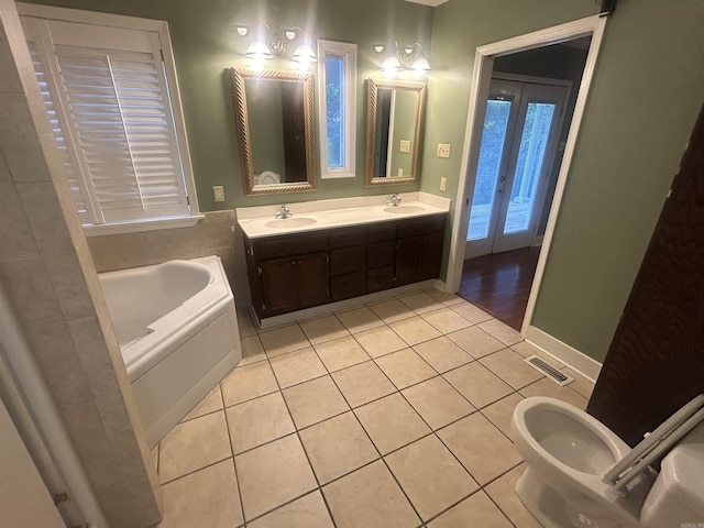 bathroom with tile patterned flooring, a bath, visible vents, and a sink