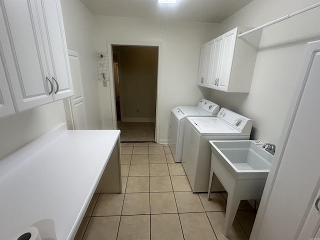 washroom with washing machine and dryer, light tile patterned floors, cabinet space, and a sink