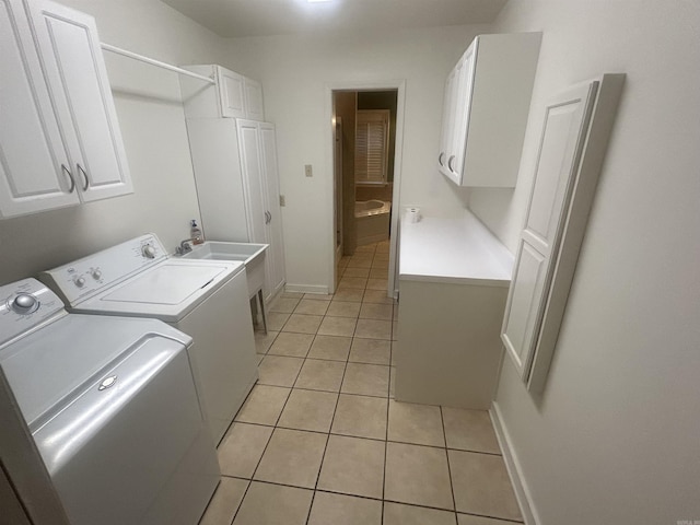 laundry area featuring washing machine and clothes dryer, light tile patterned floors, cabinet space, and baseboards