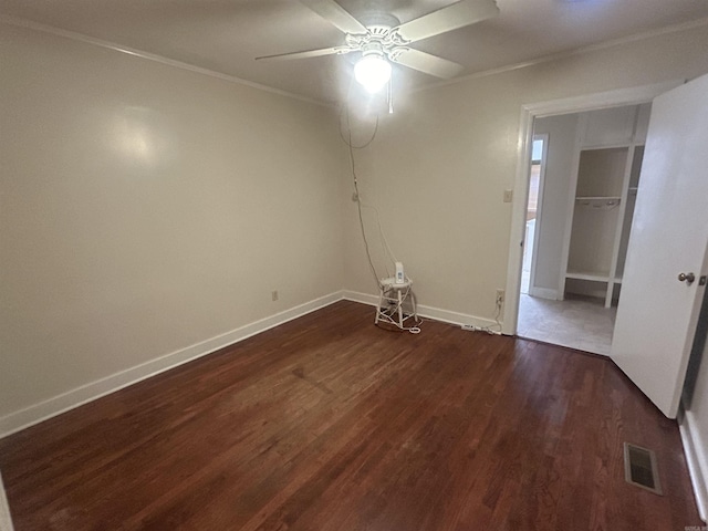 interior space with visible vents, ceiling fan, baseboards, ornamental molding, and dark wood-style floors