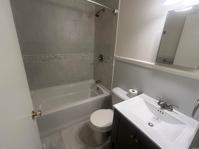 full bathroom featuring vanity, tiled shower / bath, and toilet