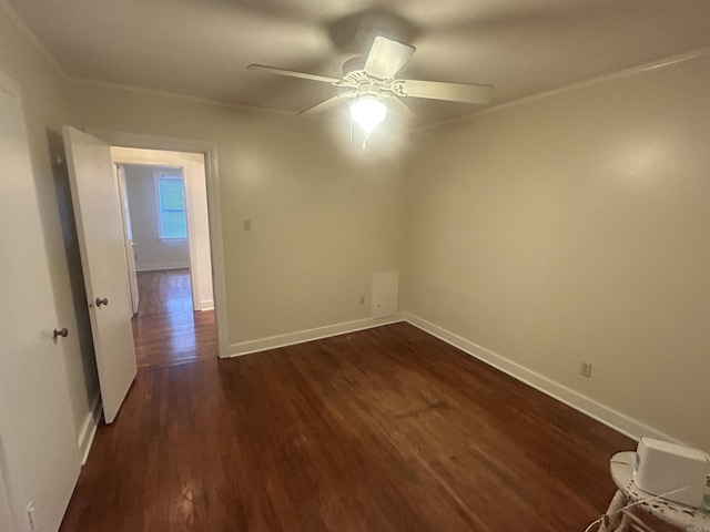 spare room featuring baseboards, dark wood-type flooring, a ceiling fan, and crown molding