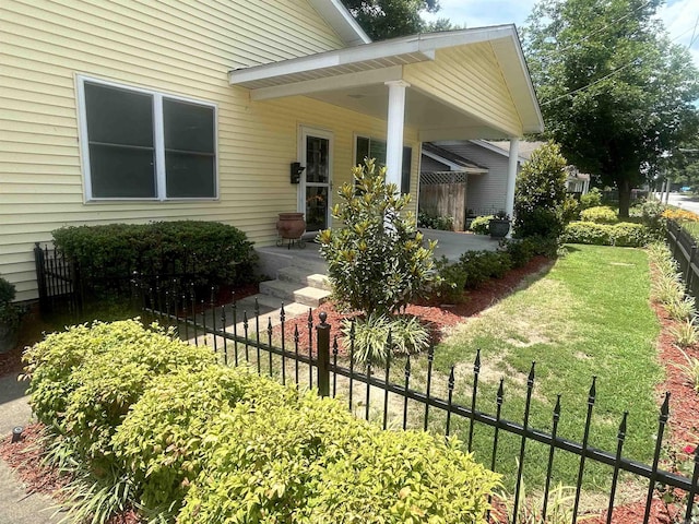 doorway to property with fence and a lawn