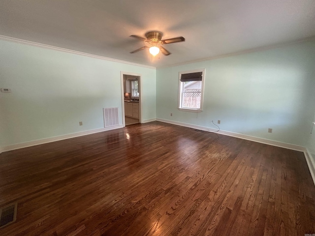 unfurnished room with baseboards, dark wood-style floors, visible vents, and ornamental molding