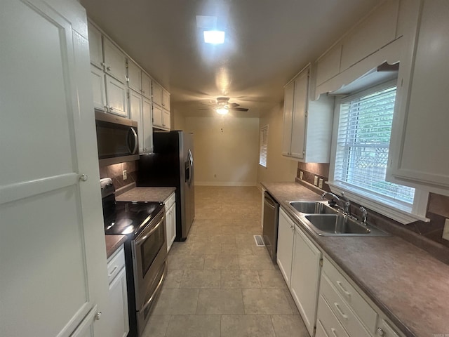 kitchen with ceiling fan, decorative backsplash, white cabinets, stainless steel appliances, and a sink