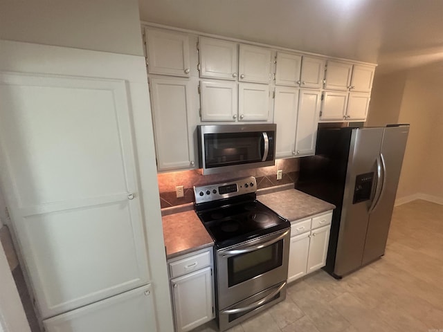 kitchen with decorative backsplash, white cabinetry, and stainless steel appliances