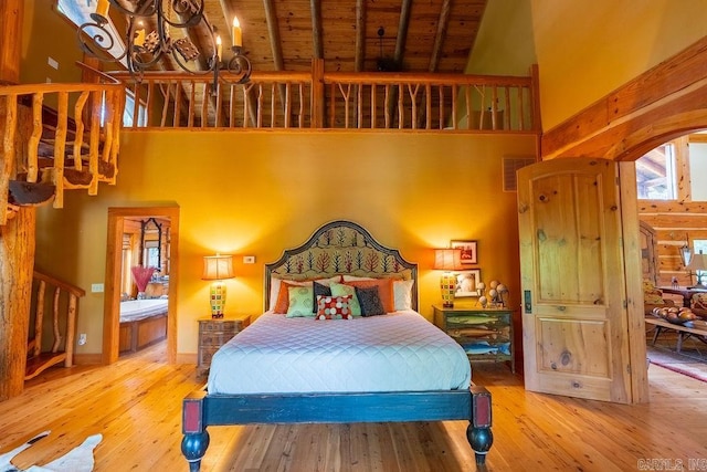 bedroom featuring wooden ceiling, high vaulted ceiling, an inviting chandelier, light wood-type flooring, and beam ceiling