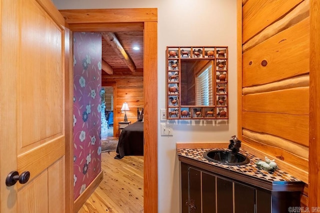 interior space featuring beam ceiling, vanity, and wood-type flooring