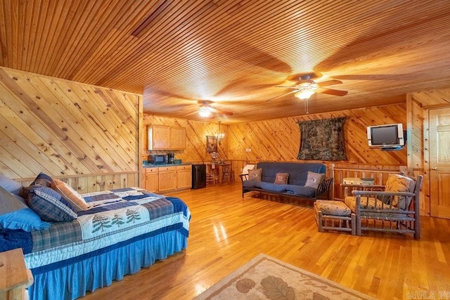 bedroom with wooden walls, ceiling fan, and light wood-type flooring