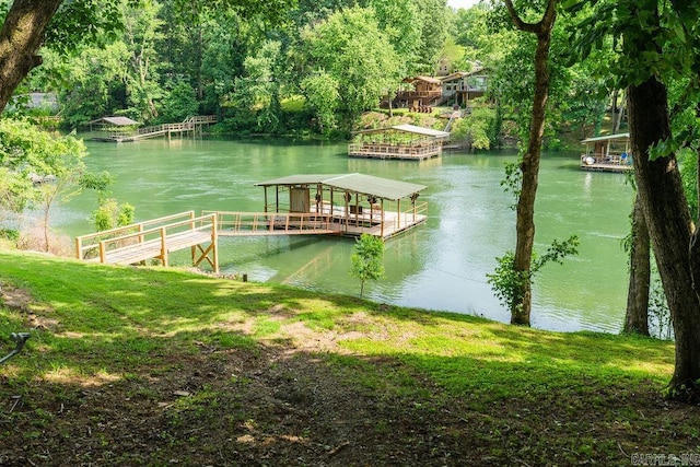 view of dock with a lawn and a water view