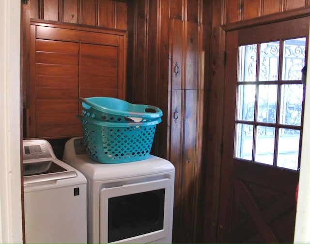 clothes washing area with washer and clothes dryer and wood walls