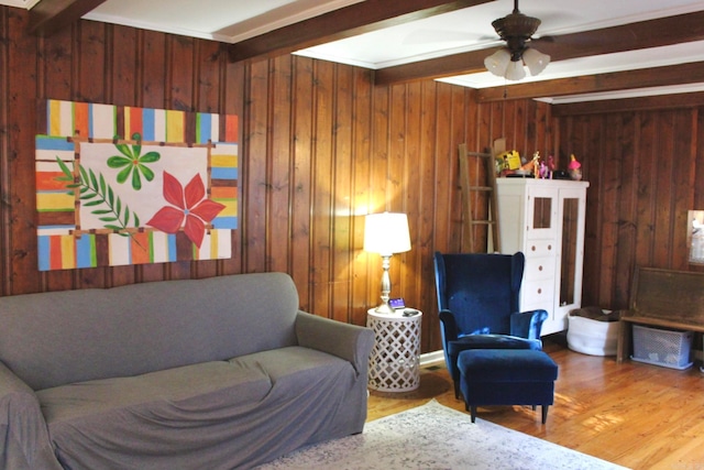 living room featuring beam ceiling, ceiling fan, wood walls, and hardwood / wood-style floors