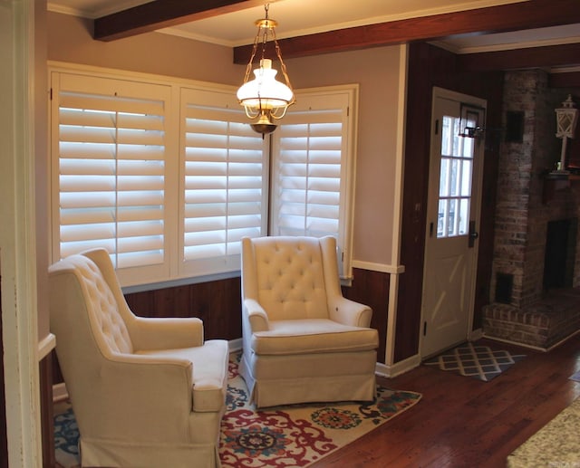 living area with beam ceiling, ornamental molding, dark hardwood / wood-style floors, and a fireplace