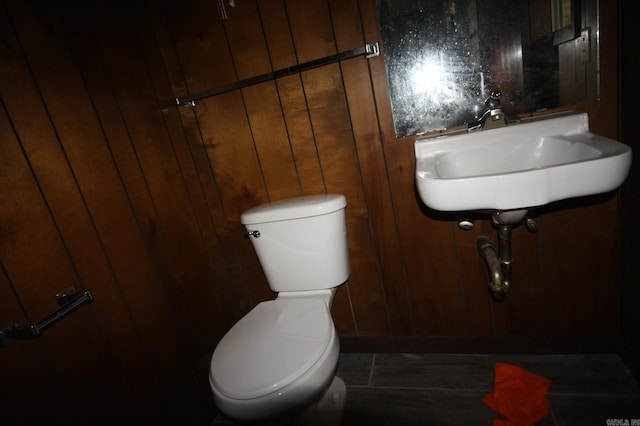 bathroom featuring sink, wooden walls, and toilet